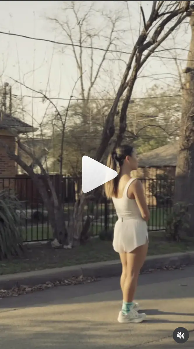 Balega ad: a woman in a white tank and shorts standing on a tree-lined street.
