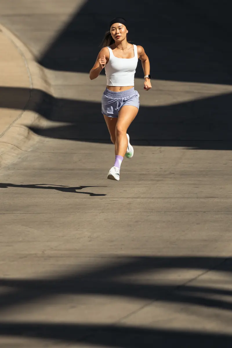 Lizzie running toward the camera across sunlit pavement.